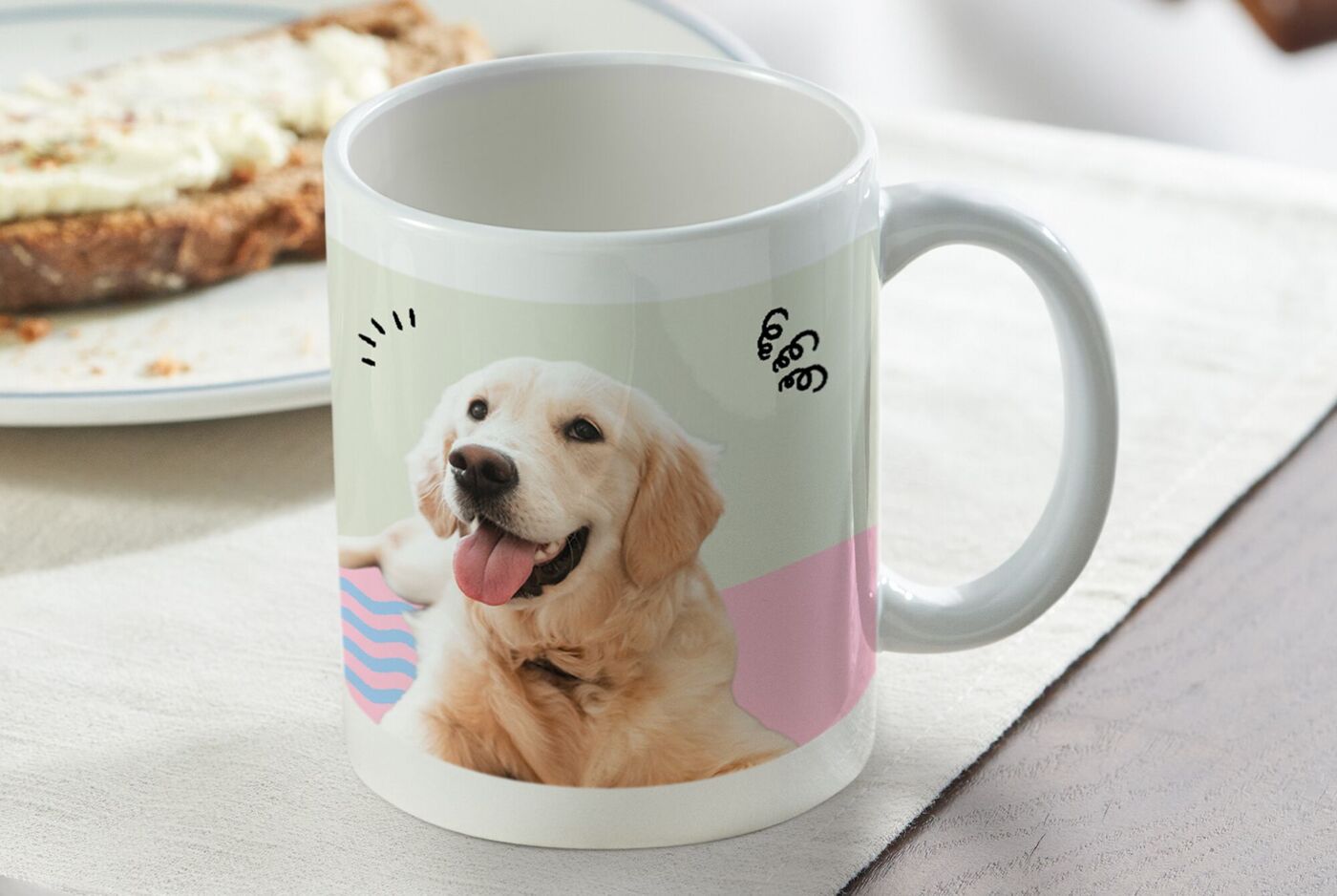 Tasse mit Foto eines fröhlichen Golden Retrievers mit buntem Hintergrund auf einem gedeckten Tisch.