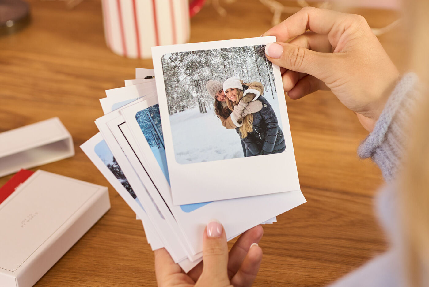 Hand hält eine Fotokarte mit zwei lächelnden Personen im Schnee.
